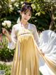 A woman in a yellow and white dress holding a white flower.