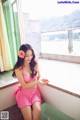 A woman in a pink bathing suit sitting in a bathtub.