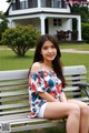 A woman sitting on a bench in front of a house.