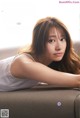 A woman laying on top of a couch next to a book.