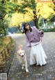 A woman walking a dog on a leash in a park.