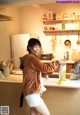 A woman standing in a kitchen holding a bag of food.