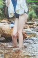 A woman standing in a stream with a towel on her head.