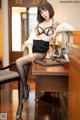 A woman sitting at a desk in a black and white outfit.