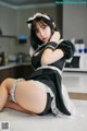 A woman in a maid outfit sitting on a kitchen counter.