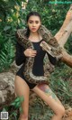 A woman in a black bodysuit holding a large snake.