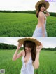 A woman in a white dress and a straw hat in a field.