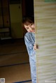 A woman in pajamas peeking out from behind a wall.