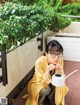 A woman sitting on a balcony holding a white watering can.