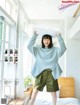 A woman standing on a bed holding a pillow over her head.