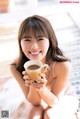 A woman sitting on the floor holding a cup of coffee.