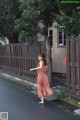 A woman in a pink dress is walking down the street.