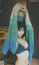 A woman in a blue bra and a green and blue sweater.
