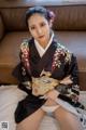 A woman in a kimono sitting on a bed.