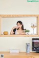 a woman sitting on top of a wooden shelf next to a tv