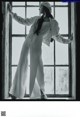 A woman standing in front of a window with her arms outstretched.