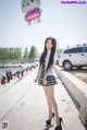 A woman in a school uniform holding a hello kitty balloon.