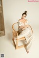 A woman sitting on a wooden chair in a room.