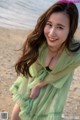 A woman in a green dress standing on a beach.