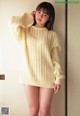 A woman in a yellow sweater is posing for a picture.