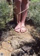 A person tied up with a rope on a dirt road.