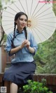 A woman sitting on a bench holding an umbrella.